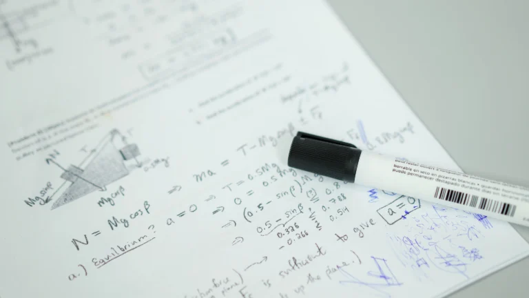 Na zdjęciu widać wzory matematyczne napisane na papierze kancelaryjnym, z których wynika że jest to artykuł poświęcony matematyce szkolnej