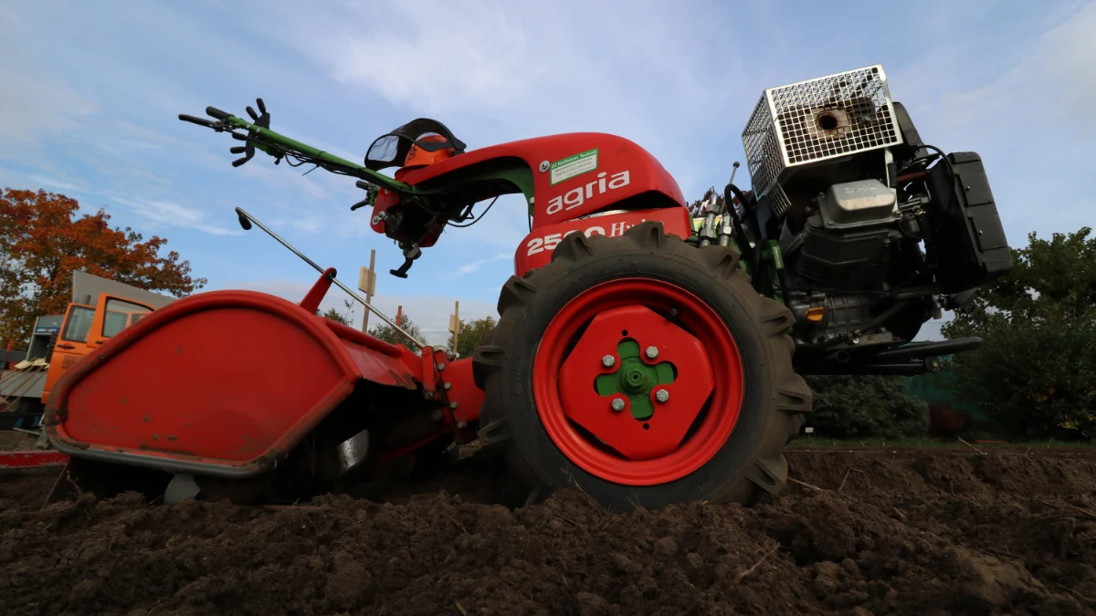 Czerwony dwukołowy traktor orzeźnia wiejskie pole, symbolizujące rolnictwo i agroogrodnictwo